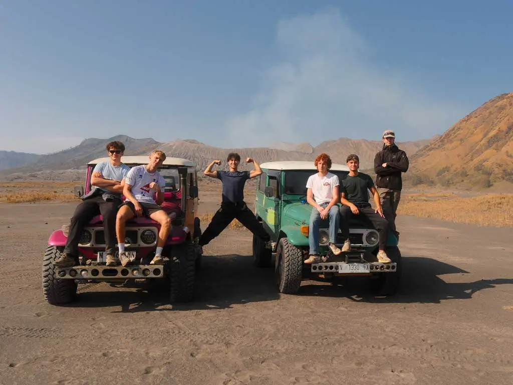 This is a photo of tourists on a 4x4 jeep on the Bromo Sea of Sand, with Mount Bromo Volcano in the background.